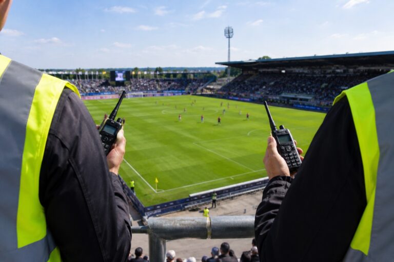 Agents en gilets jaunes, talkie-walkie en main, face à un stade en match : le PoC coordonne la sécurité des événements
